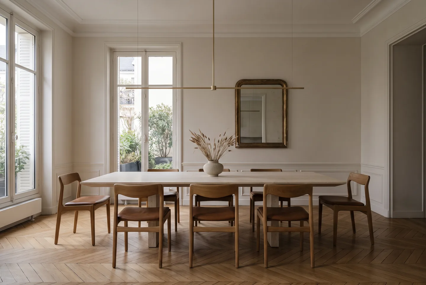 Salle à manger de l’hôtel particulier : table en pierre massive, suspension en laiton, miroir ancien