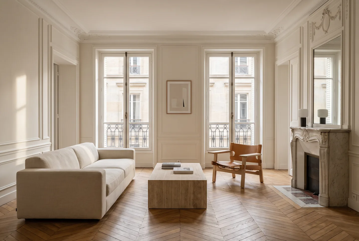Salon haussmannien rénové : parquet à chevrons, moulures d’origine, cheminée en marbre et balcons filants
